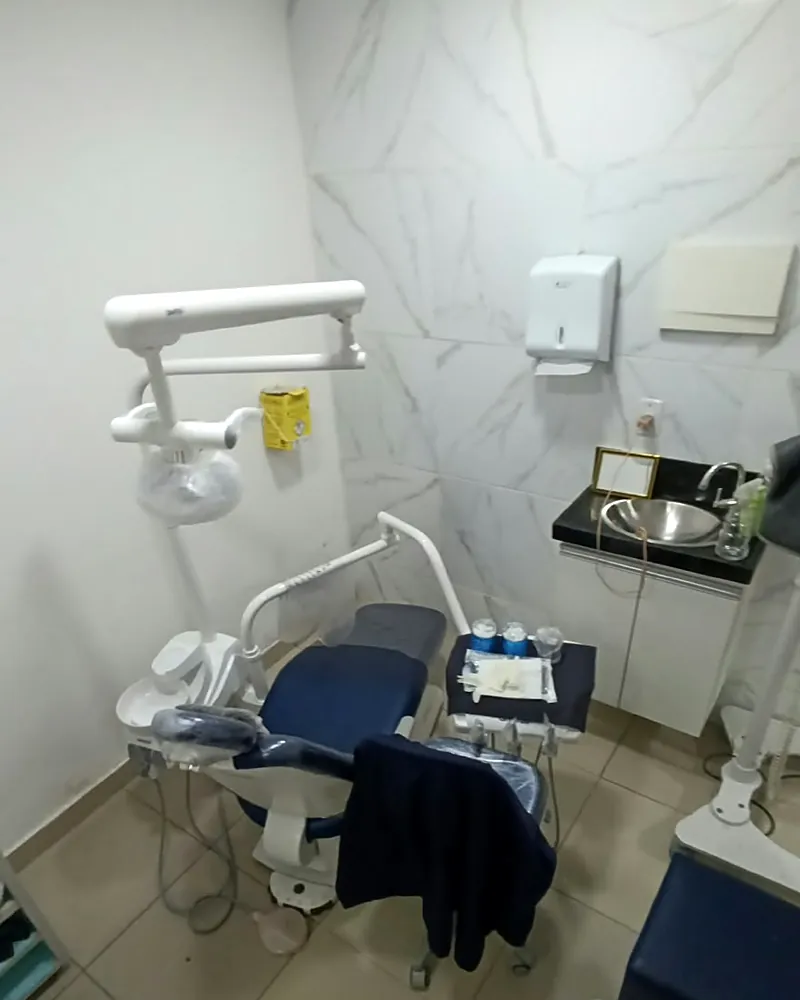 Consultório da Oral Sollution com cadeira odontológica azul e parede de mármore
