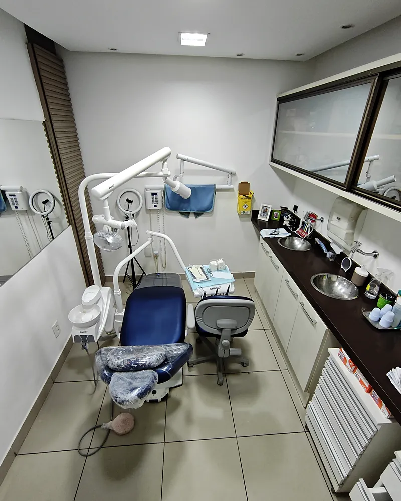 Consultório da Oral Sollution com cadeira odontológica azul e bancada
