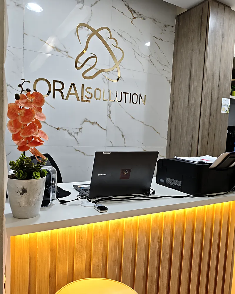 Balcão da recepção da Oral Sollution com o logo na parede de mármore